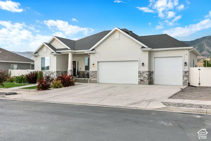 Contemporary stucco exterior with stone accents, featuring a covered porch entry and a two-car garage