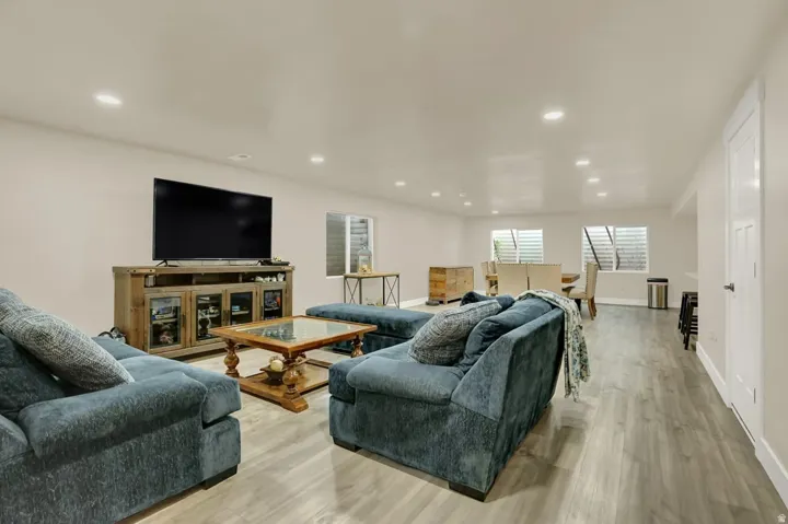 Spacious open-concept living area featuring light wood-finish flooring, recessed lighting, and egress windows