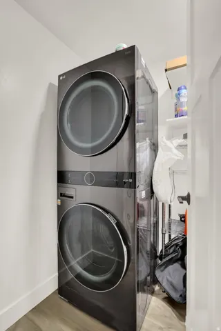 Stacked dark finish laundry appliances with a wood-finish floor