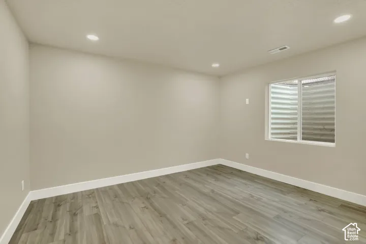 Spacious room featuring wood-finish flooring, recessed lighting, and a neutral wall color