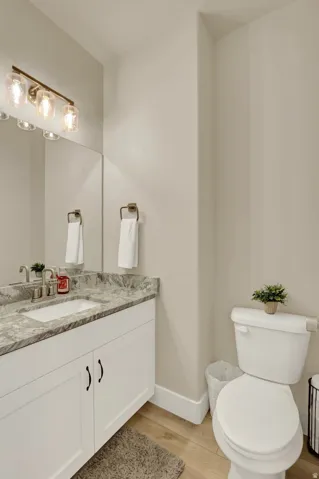 Bathroom featuring a white vanity with an undermount sink, a gray patterned countertop, and brushed brass hardware