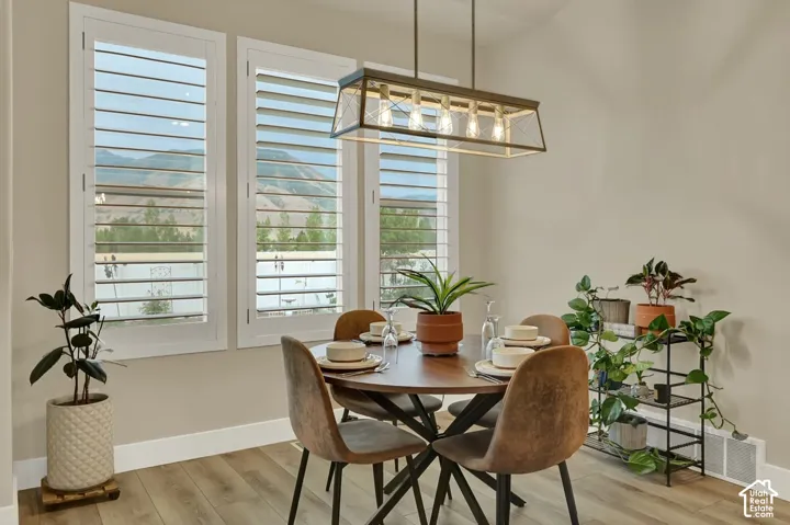 Dining area featuring a contemporary linear chandelier and light wood-finish flooring