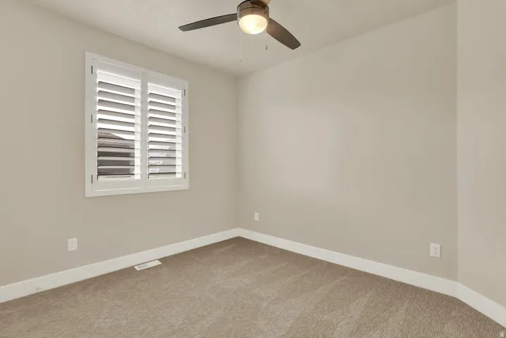 Neutral-toned interior with a window featuring white plantation shutters