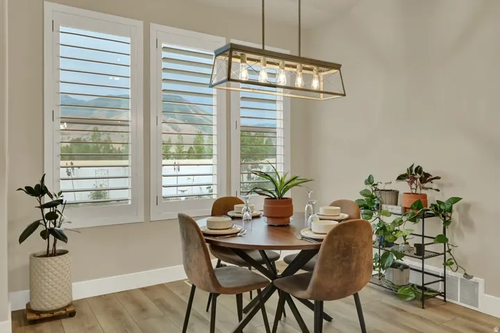 Dining area featuring a contemporary linear chandelier and light wood-finish flooring