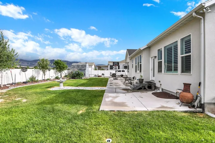 Expansive backyard featuring a manicured lawn and a concrete patio