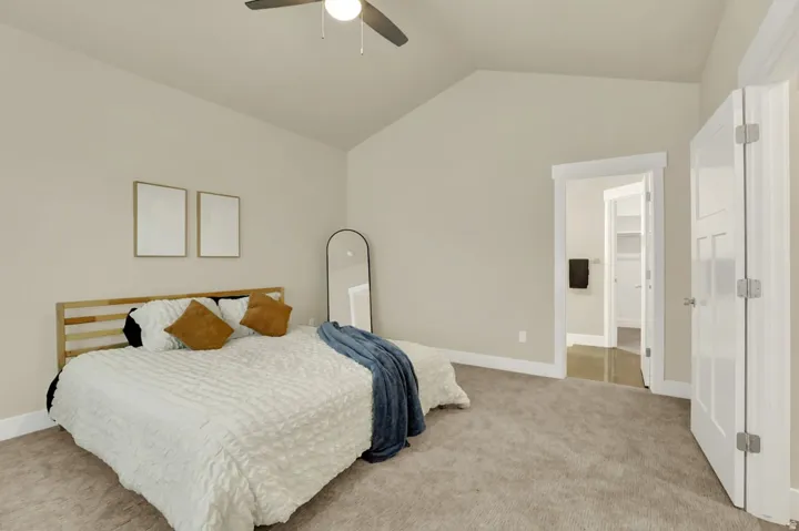 Bedroom featuring vaulted ceilings, carpeted flooring, a ceiling fan with integrated lighting, and white trim throughout