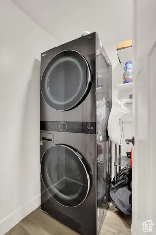 Stacked dark finish laundry appliances with a wood-finish floor