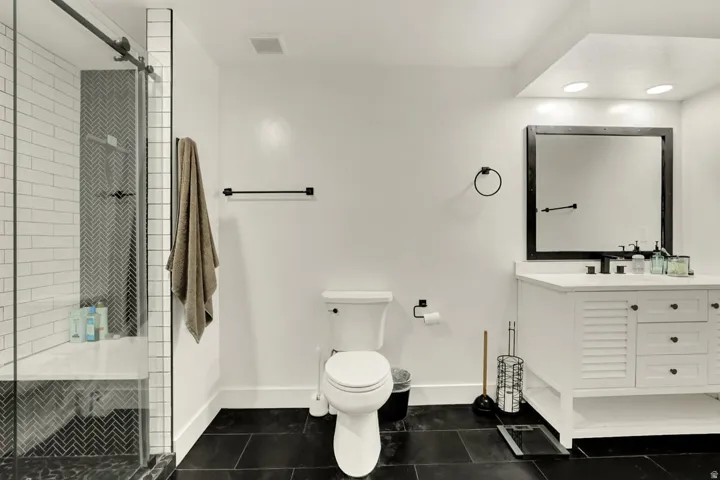 Bathroom featuring a glass-enclosed shower with a built-in bench, white subway tile, and a dark herringbone accent wall