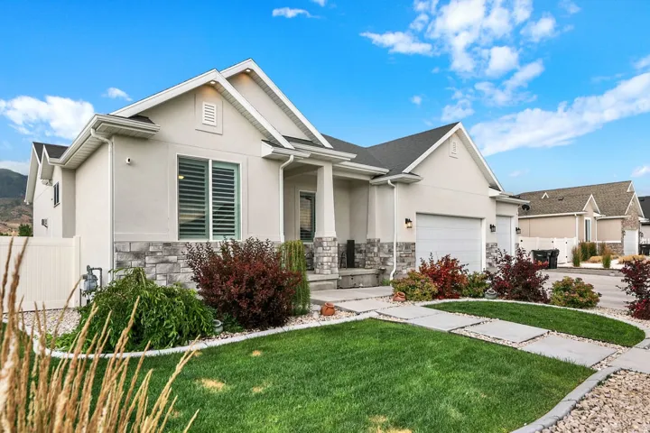Light stucco exterior with a stone veneer accent, featuring a two-car garage and a covered entry