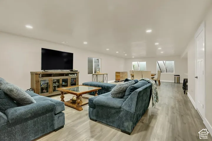 Spacious open-concept living area featuring light wood-finish flooring, recessed lighting, and egress windows