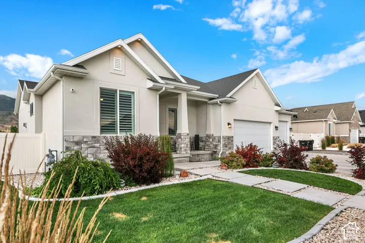Light stucco exterior with a stone veneer accent, featuring a two-car garage and a covered entry