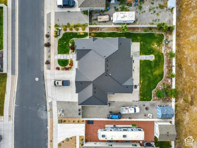 Residential property featuring a dark shingle roof, a paved driveway, and a front yard with manicured lawn and mature landscaping
