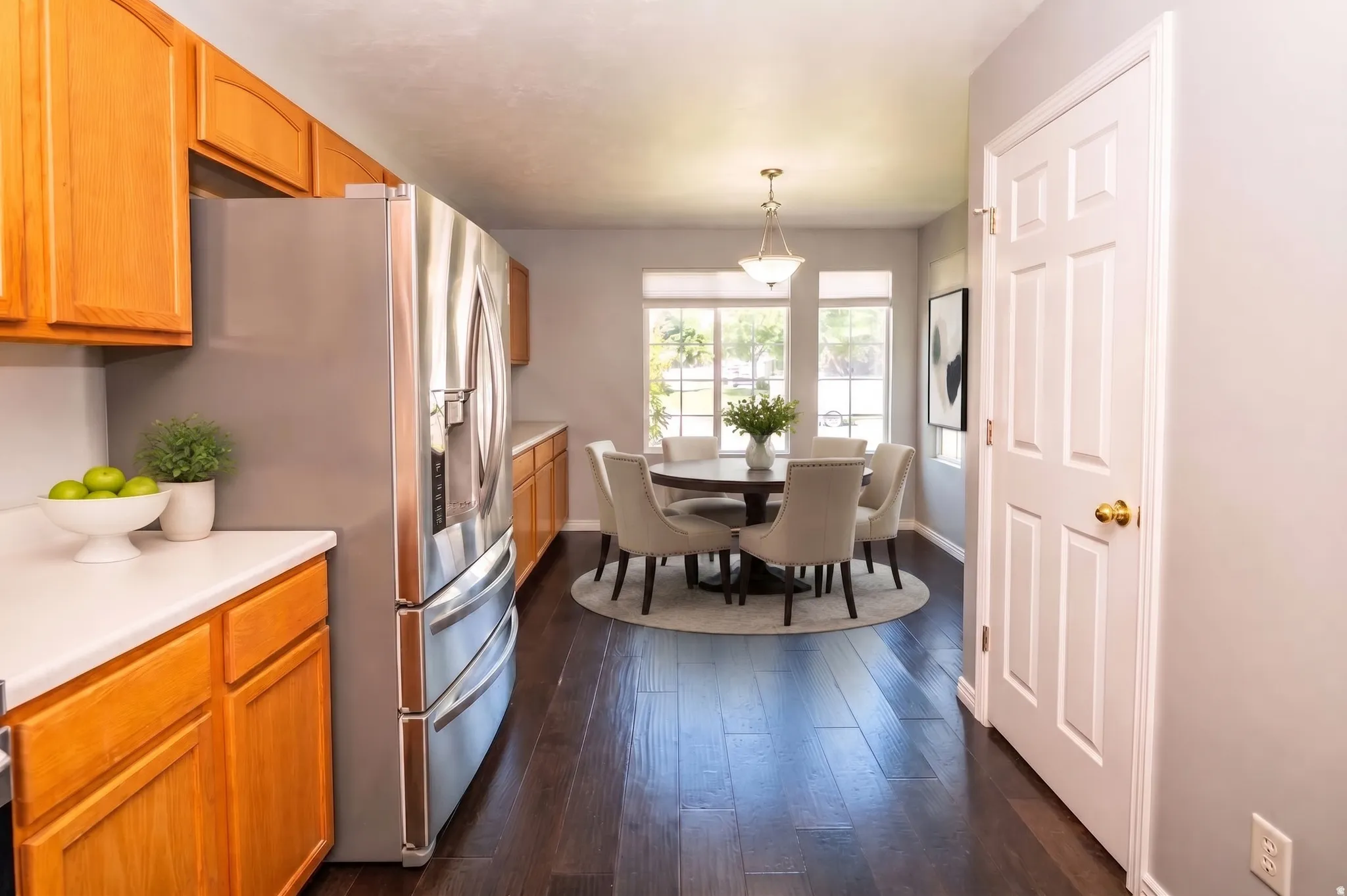 Stainless steel refrigerator with a built-in ice and water dispenser, wood-finish flooring, recessed lighting, and a white six-panel door with brass hardware