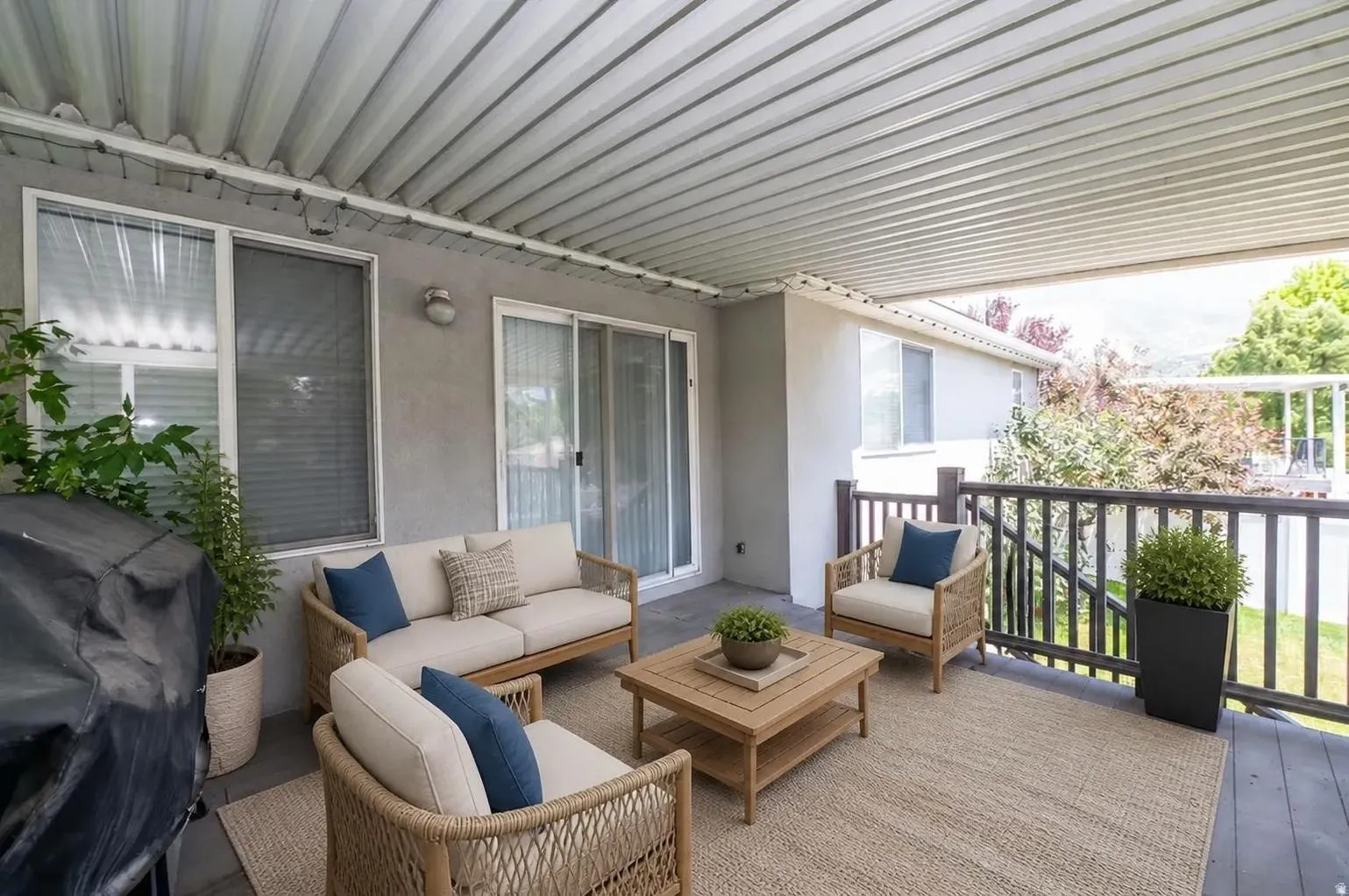 Covered patio featuring a corrugated metal ceiling, sliding glass doors, and dark wood railing