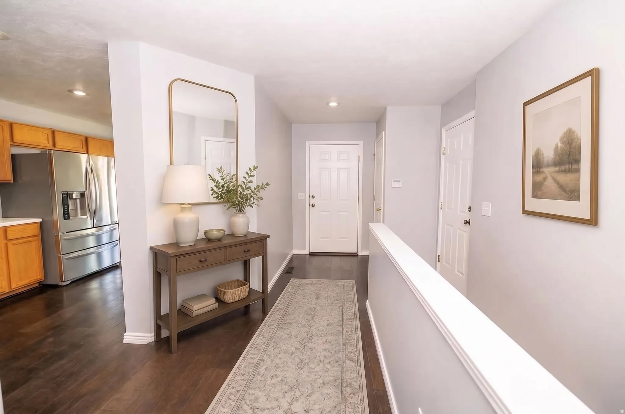Hardwood-style flooring throughout, light-toned walls, recessed lighting, and a kitchen featuring wood cabinetry and stainless steel appliances