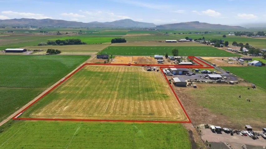 Expansive agricultural property featuring multiple buildings, cultivated fields, and open land