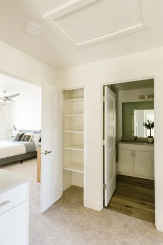 Hallway featuring light carpeting, a built-in shelving unit, and access to a bedroom and bathroom