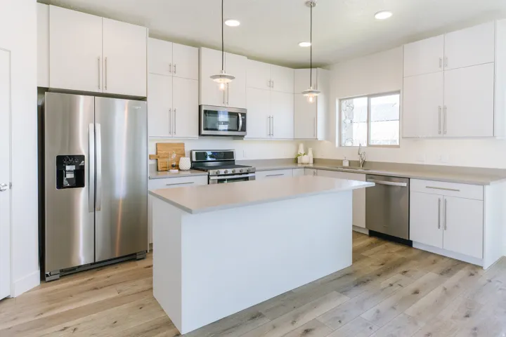 Modern kitchen with white cabinetry and wood-finish flooring
