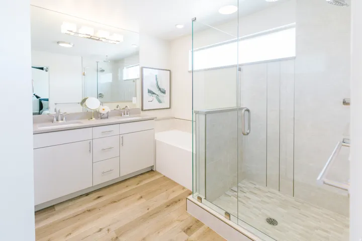 Contemporary bathroom featuring a glass-enclosed shower with tiled walls and floor, a separate soaking tub, and a dual vanity with a light-colored countertop