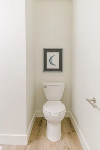 White commode in a niche with wood-finish flooring