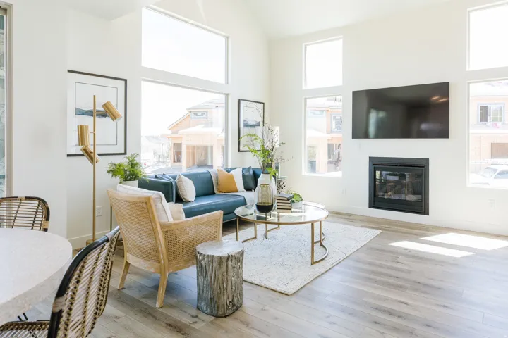 Spacious living area featuring high vaulted ceilings, large picture windows, a built-in fireplace, and wood-finish flooring