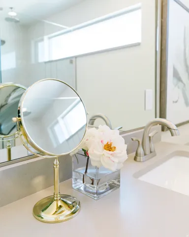 Bathroom vanity featuring a light-toned countertop, undermount sink, brushed nickel faucet, and extensive mirror