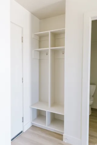 Built-in mudroom storage featuring upper shelving, coat hooks, and lower cubbies