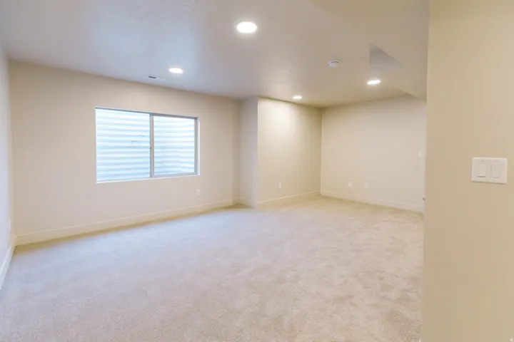 Spacious room featuring neutral carpeting, recessed lighting, and a horizontal sliding window