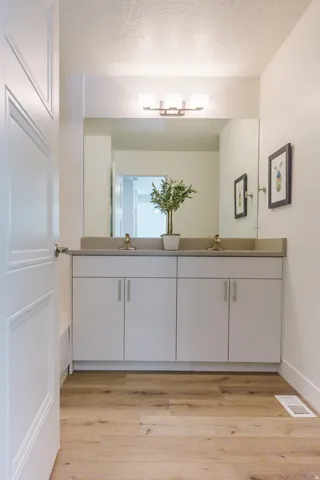 Double vanity with white cabinetry and brushed nickel hardware, featuring dual sinks and a light-toned countertop