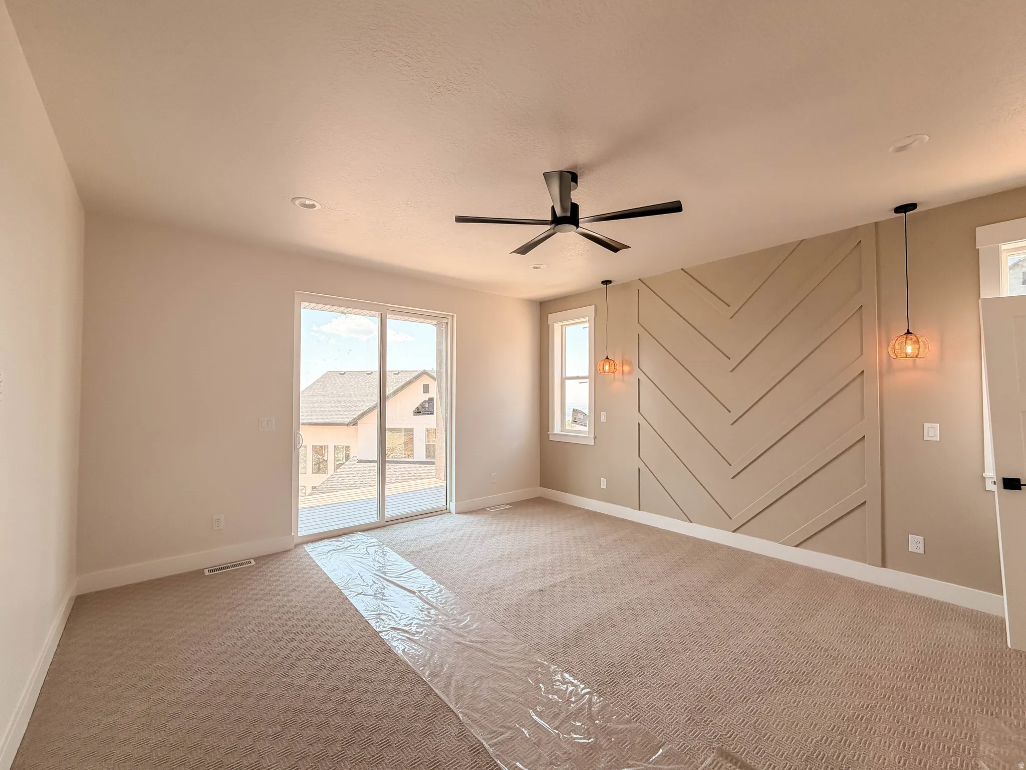 Spacious room featuring a decorative accent wall with a chevron pattern, a ceiling fan with integrated lighting, and recessed ceiling lights