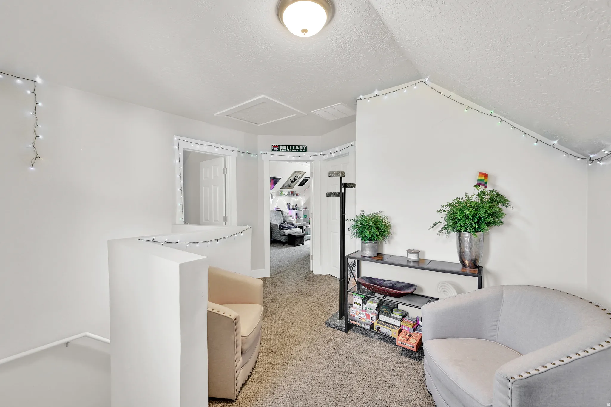 Carpeted hallway with white walls and a vaulted ceiling