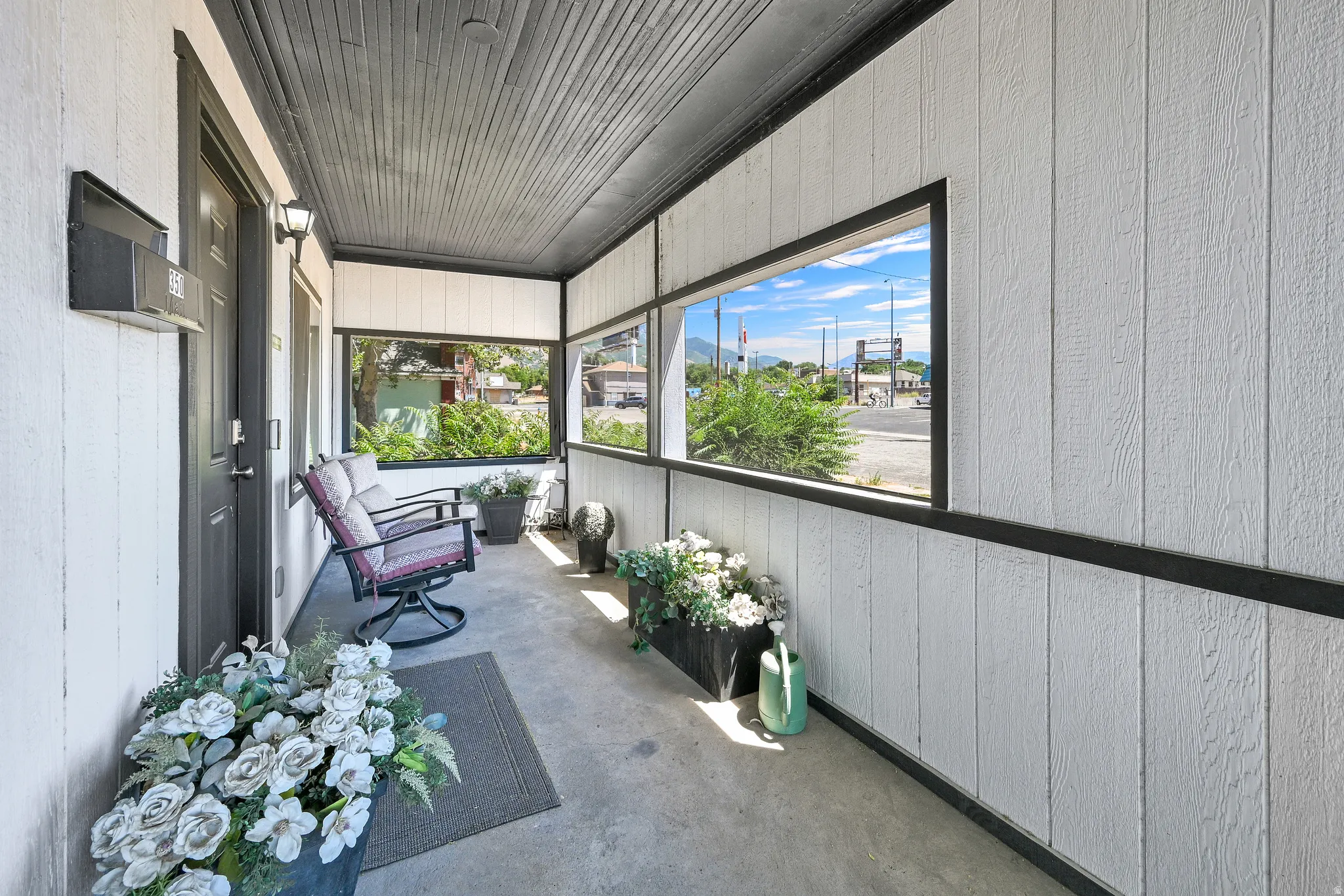Covered porch with white vertical siding and black trim