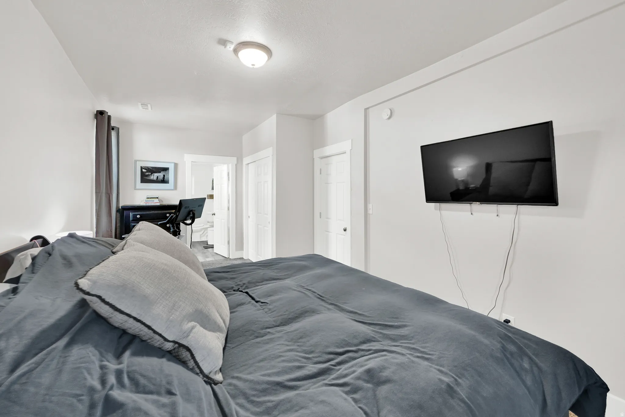 Bedroom featuring a wall-mounted television, neutral wall paint, white trim, and a ceiling-mounted light fixture