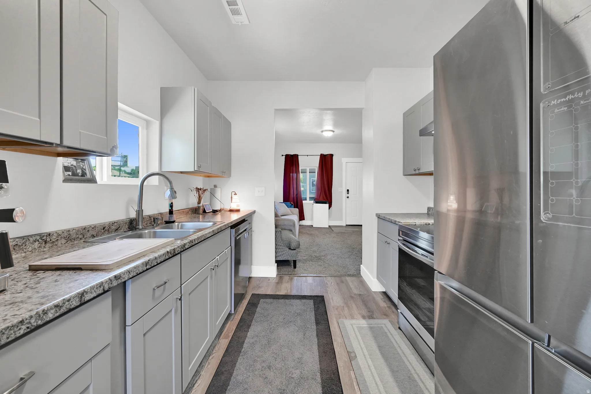 Kitchen featuring light gray cabinetry, a double basin stainless steel sink, and wood-finish flooring