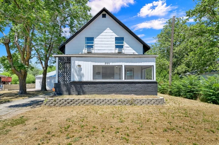 Traditional-style residence featuring white siding, a contrasting dark roof, and a front porch with a screened enclosure