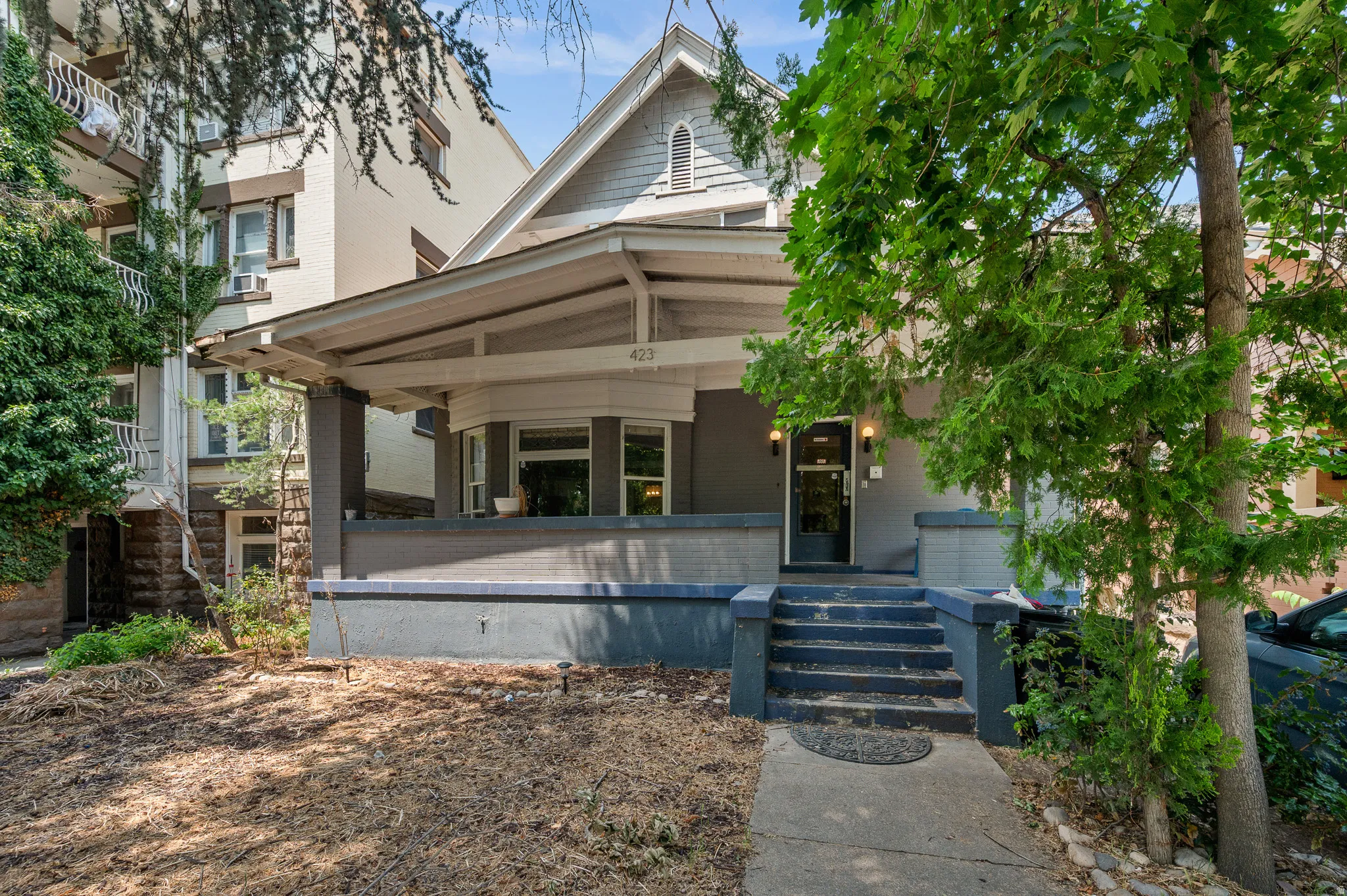 Craftsman-style home featuring a covered front porch, bay window, and a stone foundation