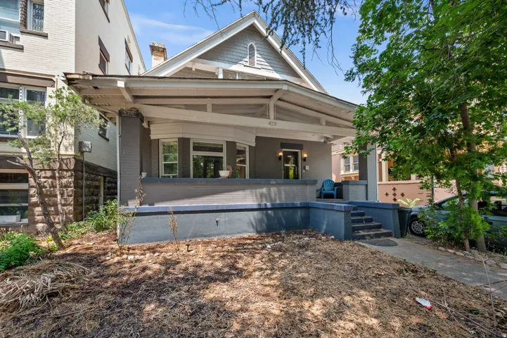 Craftsman-style facade featuring an inviting front porch with painted wood columns and a grey brick foundation