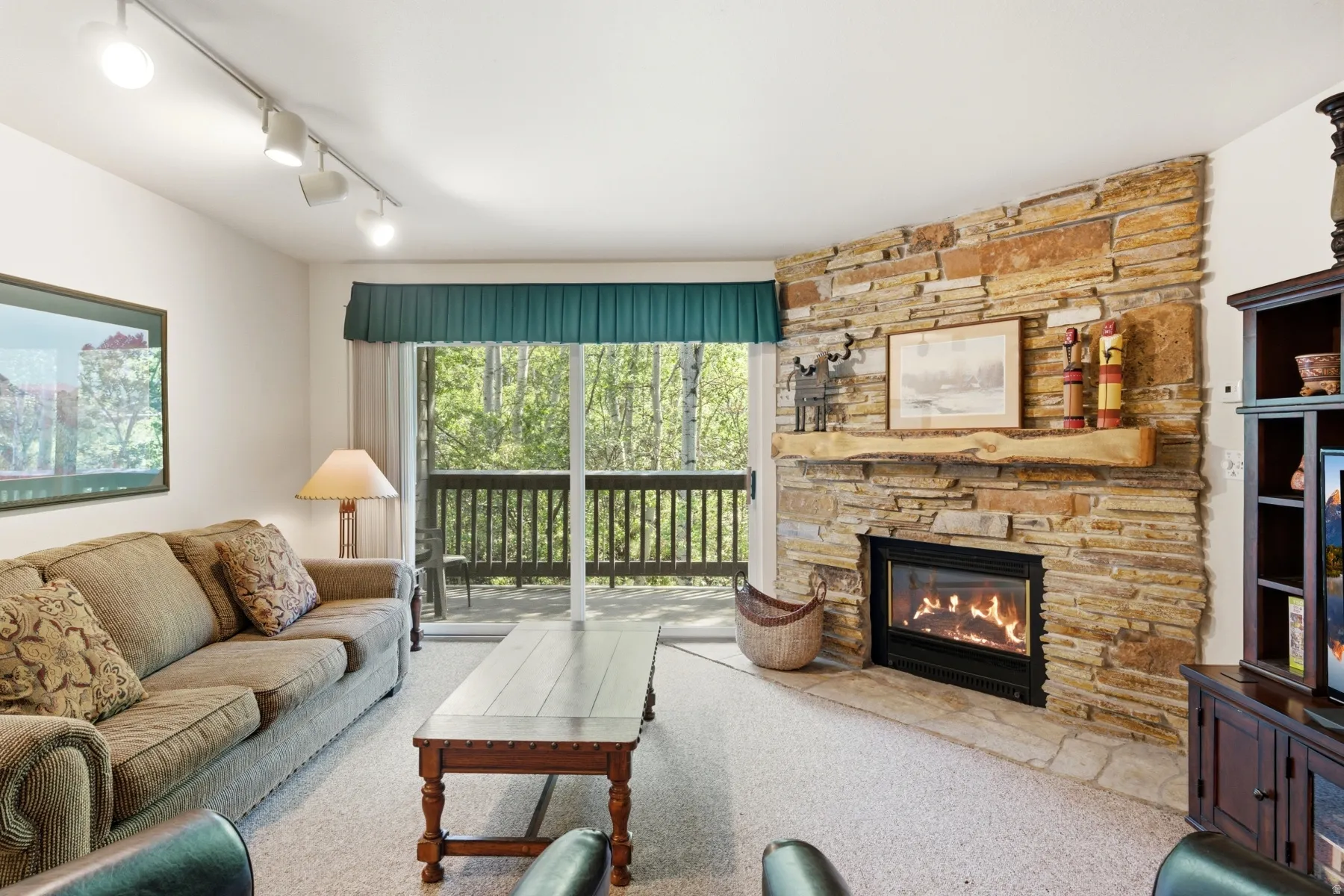 Living area featuring a floor-to-ceiling stone fireplace with a substantial timber mantelpiece