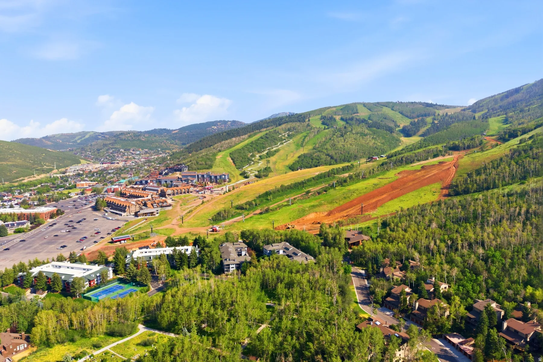 Expansive mountainous terrain with a ski resort, residential properties, and dense natural tree cover