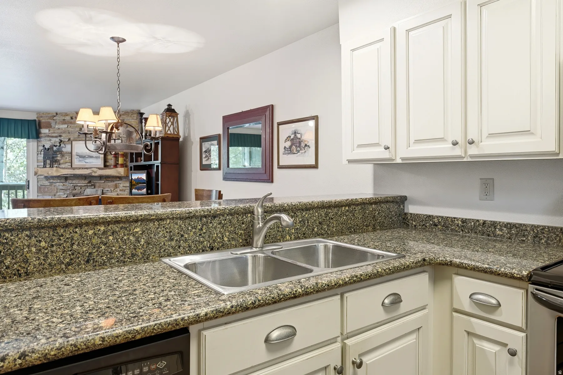 Kitchen featuring an undermount double basin sink with a single-handle faucet, light-colored cabinetry with silver hardware, and stone-finish countertops