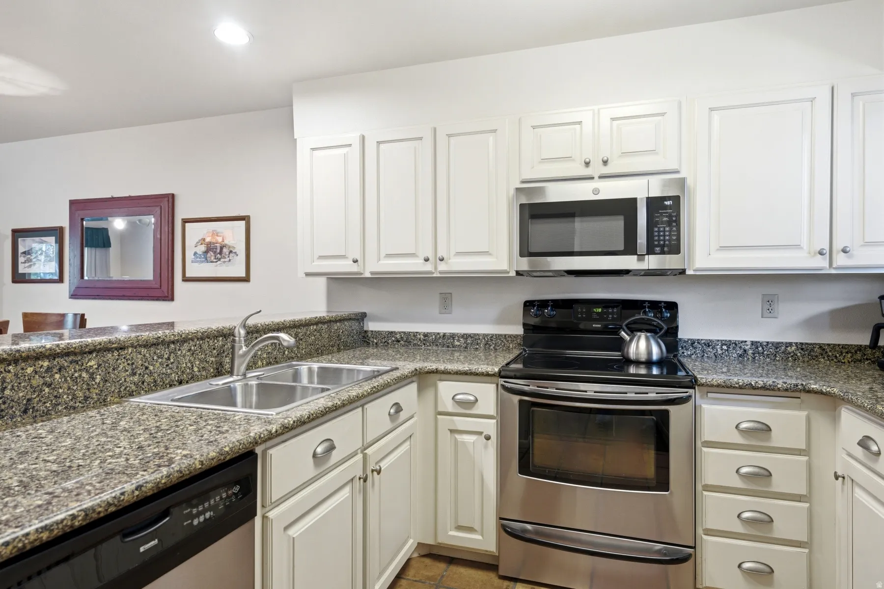 Kitchen featuring white cabinetry, speckled countertops, stainless steel appliances, a double basin sink, and a built-in microwave