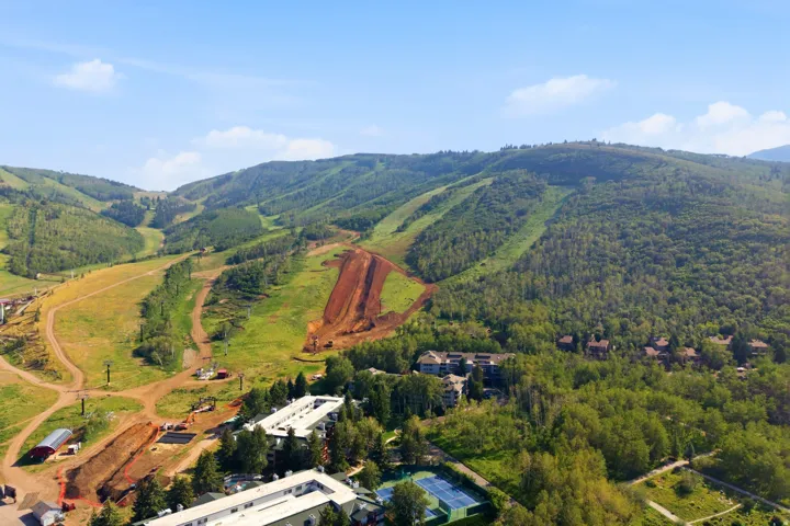 Expansive mountainous landscape featuring lush green slopes, wooded areas, and multiple structures