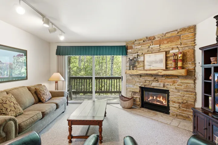 Living area featuring a floor-to-ceiling stone fireplace with a substantial timber mantelpiece