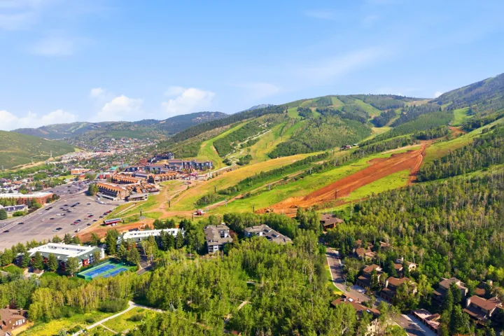 Expansive mountainous terrain with a ski resort, residential properties, and dense natural tree cover