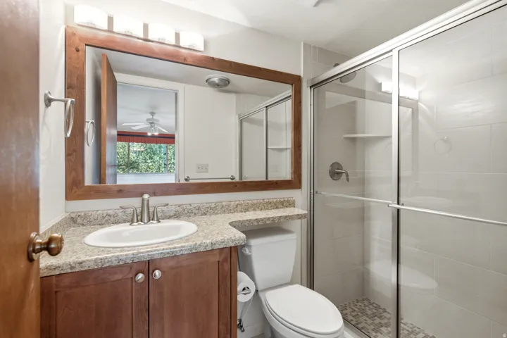 Bathroom with a wood-framed vanity mirror, a granite-finish countertop, and a wood-finish two-door vanity cabinet