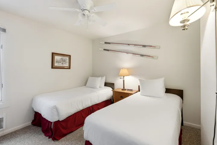 Bedroom featuring two single beds, a ceiling fan, light neutral wall paint, and carpet flooring