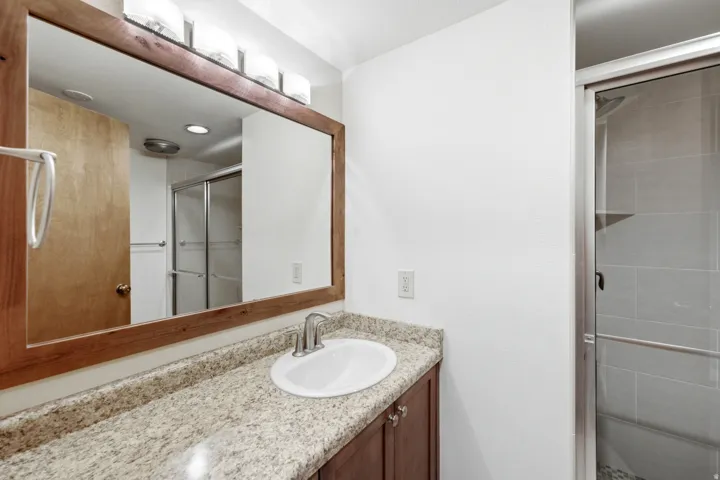 Bathroom featuring a vanity with a light-toned speckled countertop, an undermount sink, and brushed nickel hardware