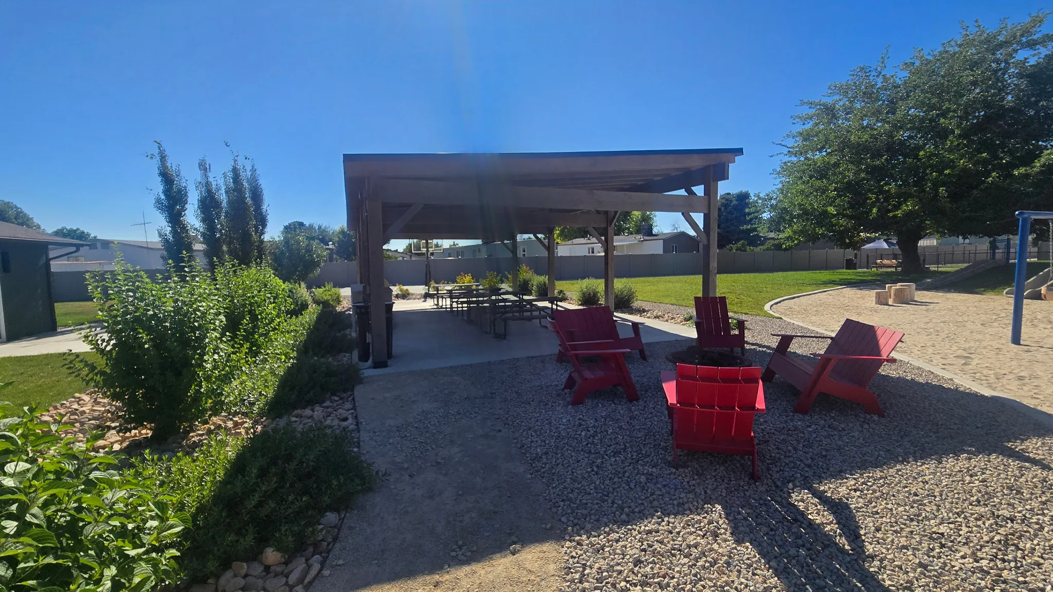 Expansive outdoor living area featuring a covered pergola, a gravel patio, and a dedicated sand play area