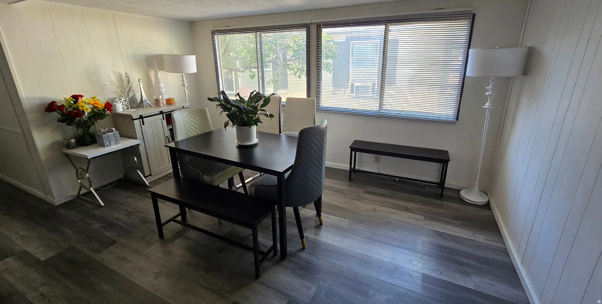 Interior space featuring wood-finish flooring, white paneled walls, and a large window with blinds