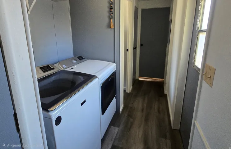 Dedicated laundry area featuring a washer and dryer, adjacent to a hallway with wood-finish flooring